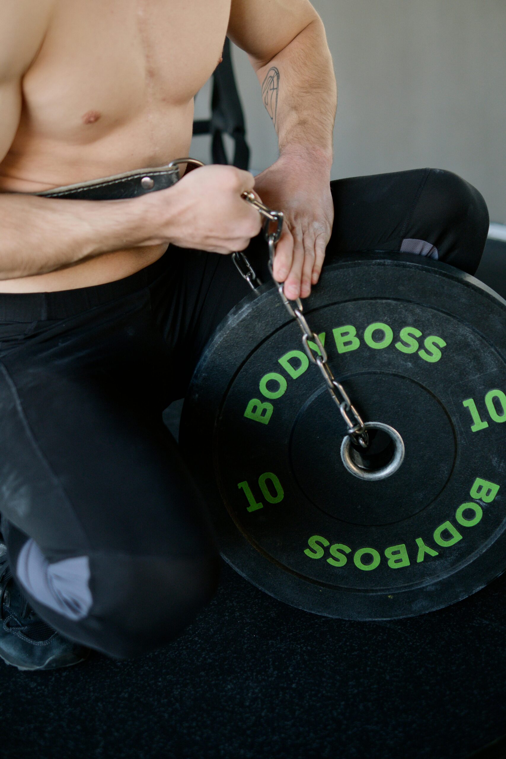 Athletic man setting up weights with chains for strength training indoors.